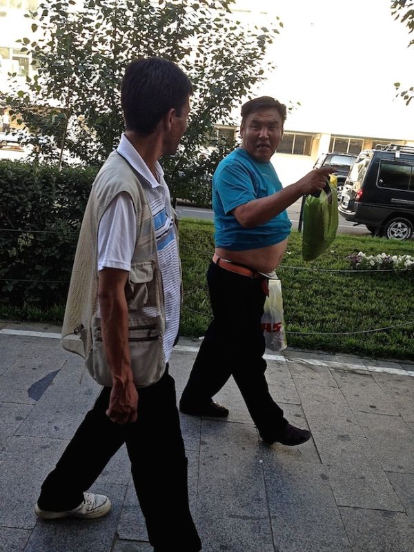 Man walking down Ulan Bator's streets with his top rolled up