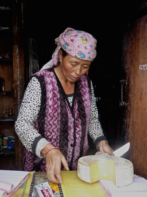 Old lady cutting some yak cheese at Chitre village