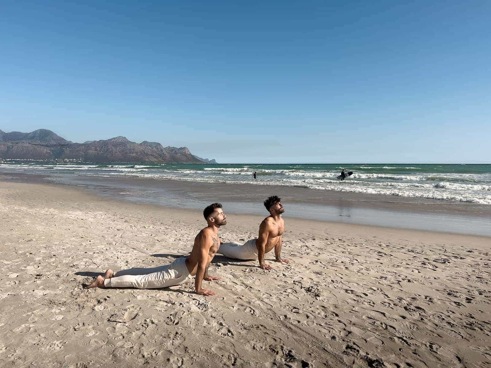 Gay couple doing yoga on the gay beach of Cape Town.