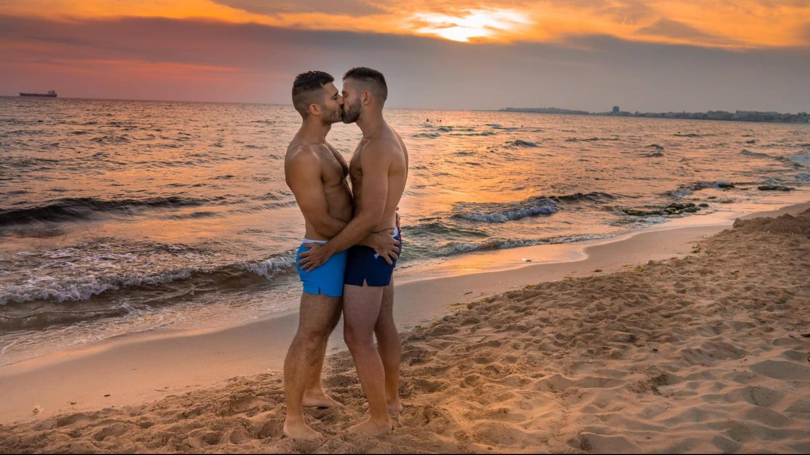 Two guys kissing in public on the beach