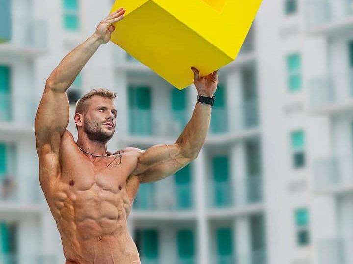 A muscly shirtless dude holding a yellow box at Johnson's gay bar in Tampa.