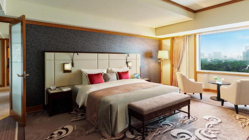 A spacious hotel room with a luxurious rug and window featuring a beautiful view over Tokyo.