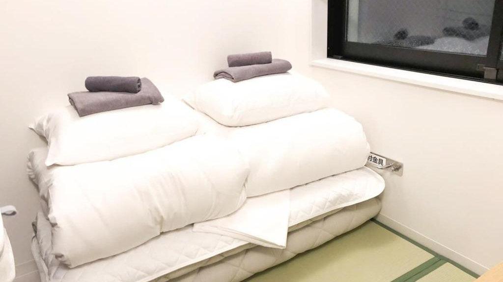 A pile of bedding ready to be transformed into a bed in a cosy capsule hotel in Tokyo.