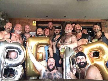 A group of men holding balloons spelling BEAR at Bear's gay bar in Sitges.