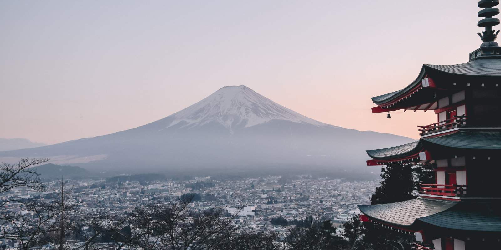 Mt Fuji in Japan as seen from a distance on a hazy day with a temple in the foreground.