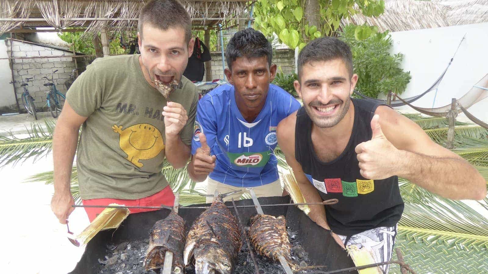 Gay couple in the Maldives cooking a fish barbecue with a local guy