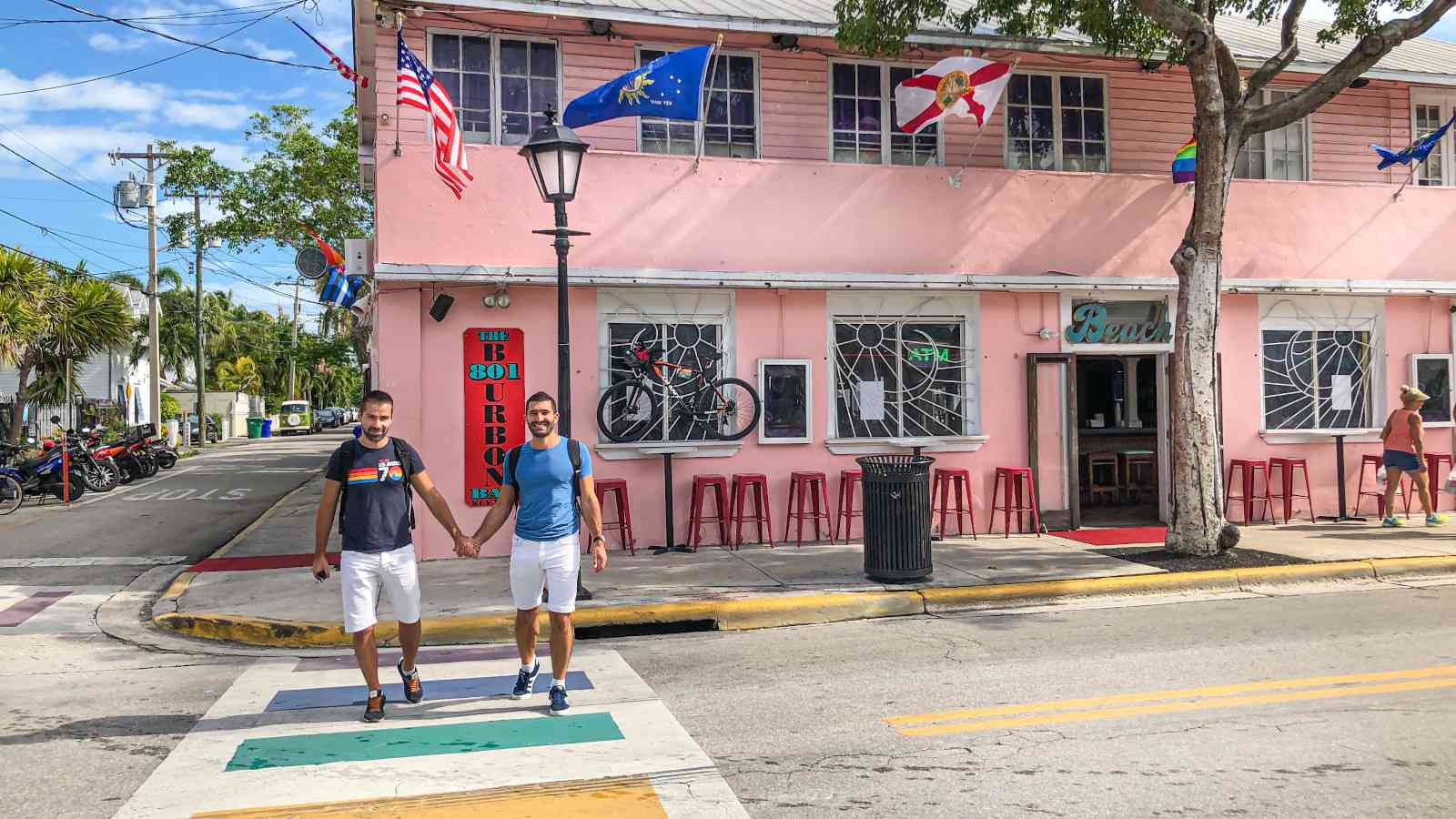 Gay couple Nomadic Boys crossing the street hand in hand in Key West