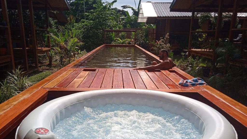 A photo taken from a hot tub next to a container swimming pool surrounded by greenery.