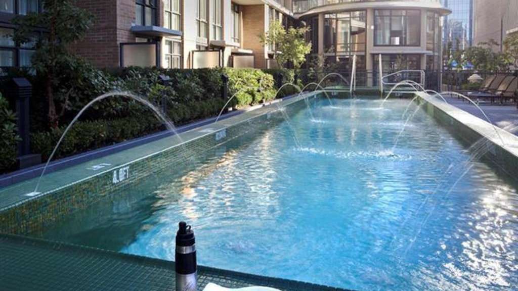 An outdoor swimming pool with fountains on all sides on a sunny day.