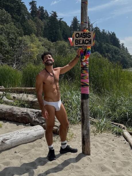 Stefan posing at Oasis sign at Wreck gay beach in Vancouver.