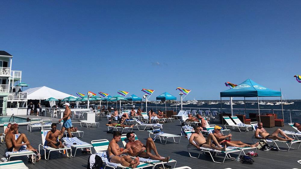 The beachside deck at Boatslip Resort in Provincetown with men sunbathing on a cloudless day.
