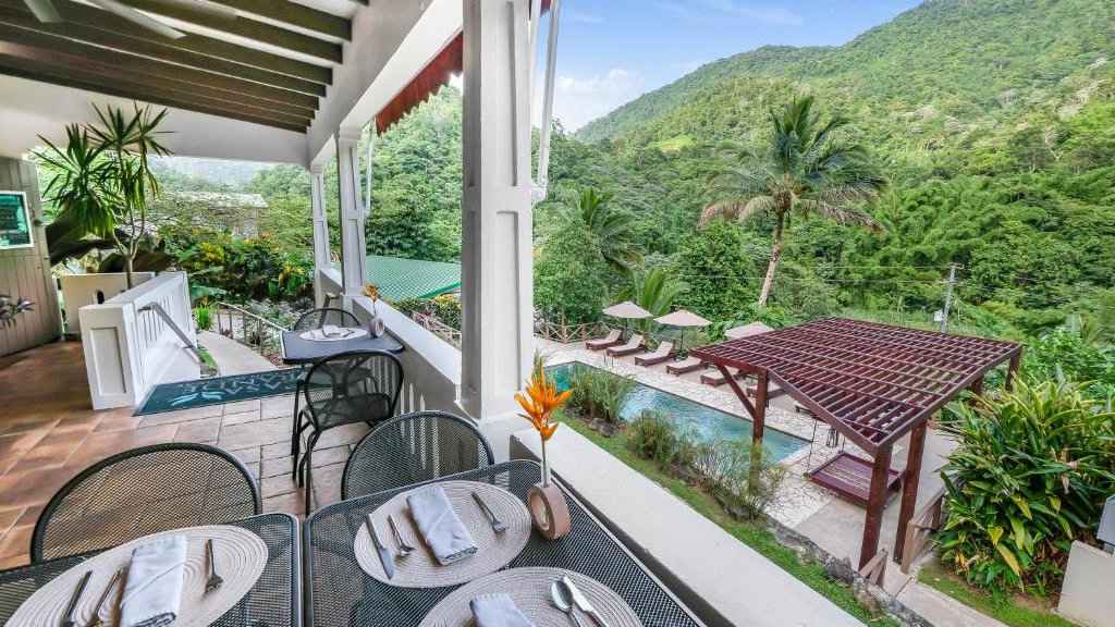 The view from a balcony in a lush green landscape with an inviting pool below.