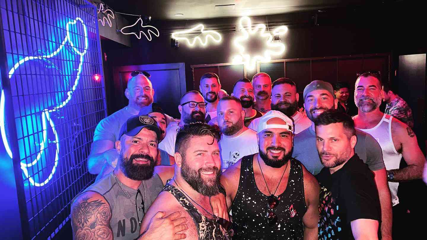 A group of muscly gay men posing in front of an LED penis at the Flex gay bar in New York City.