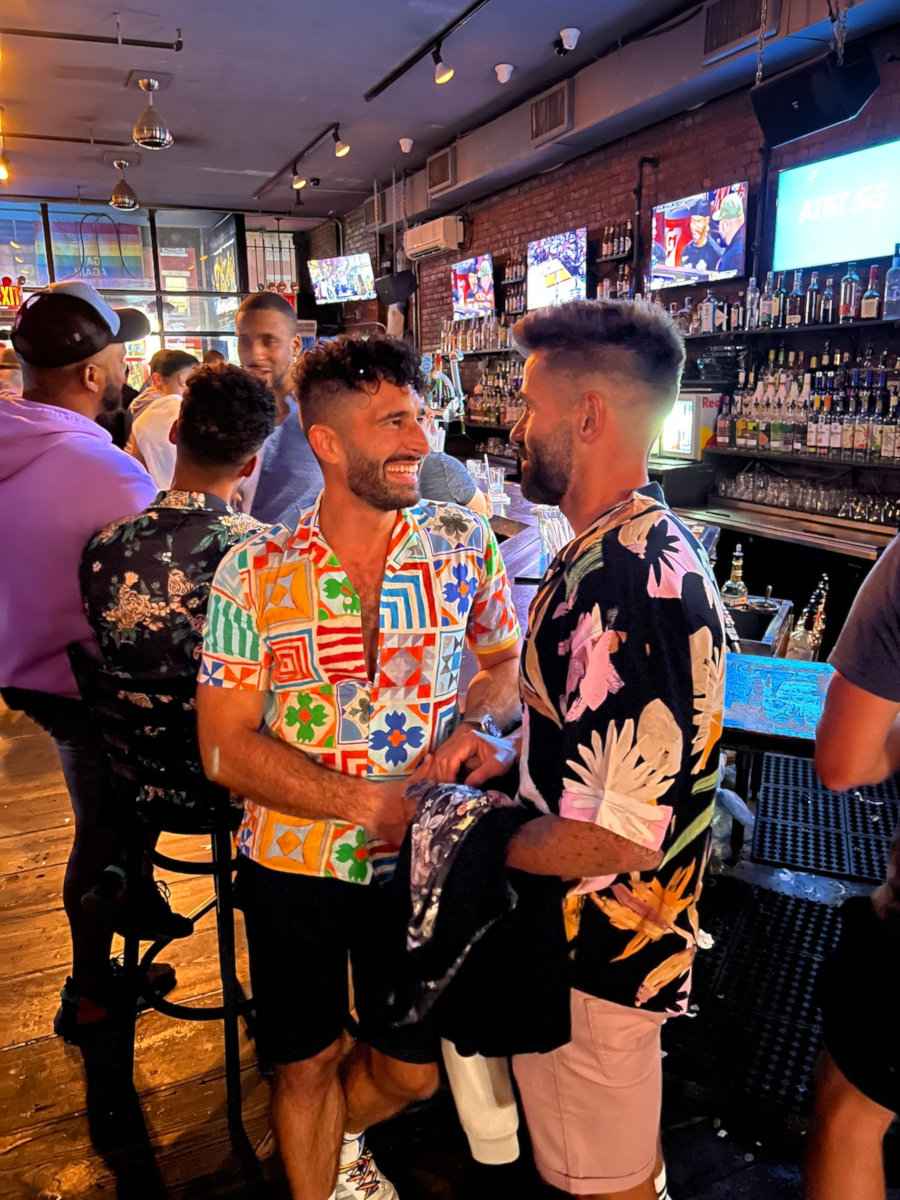 Stefan and Seby wearing colorful shirts and chatting in the gay bar Rebar in NYC.