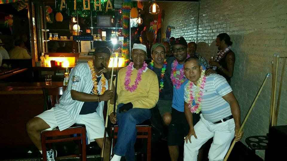 A group of men of different ethnicities posing at the bar in the Hangar Bar in New York City.