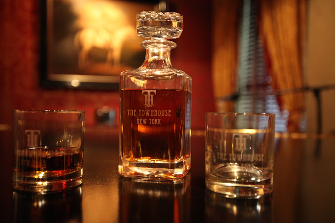 A close up of a whiskey decanter and glasses with The Townhouse New York etched on the glass.