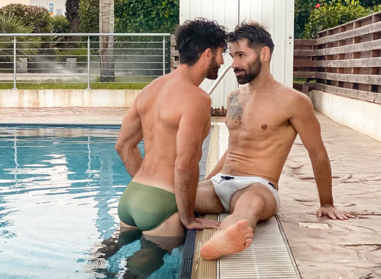 Gay couple in Speedos by pool