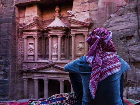 Man with Arabic kaffiyeh headscarf in front of The Treasury Building at Petra in Jordan.