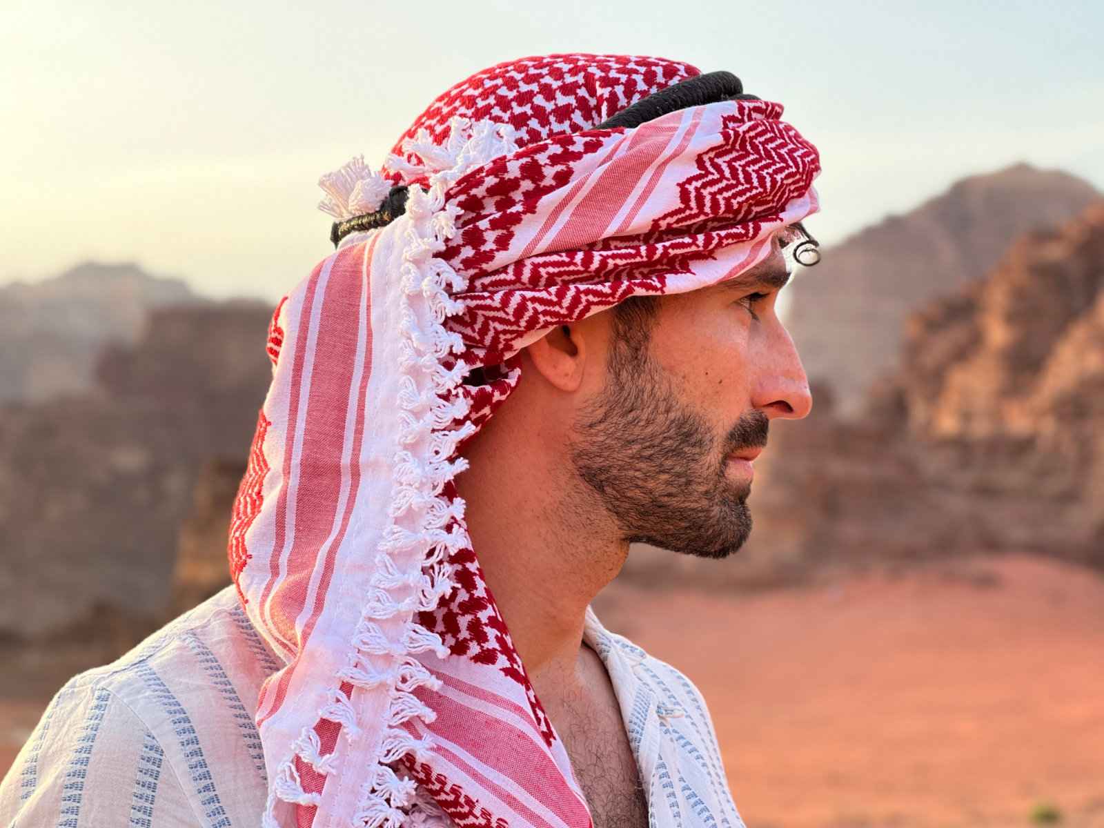 Stefan from Nomadic Boys gay travel blog posing with a headscarf in the desert of Jordan. 
