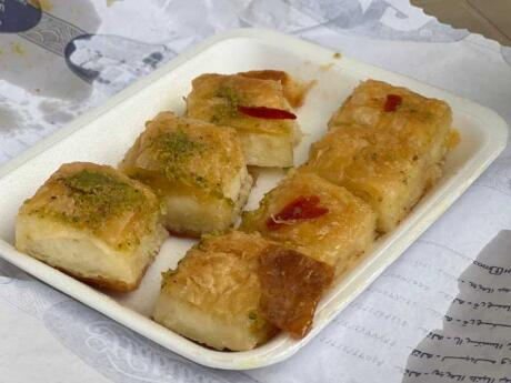 Small squares of a pastry food on a white plate from habibah Sweets in Amman.