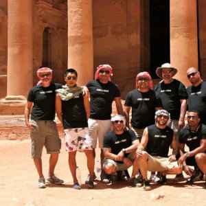 A group of men in dark t-shirts posing outside Petra in Jordan.