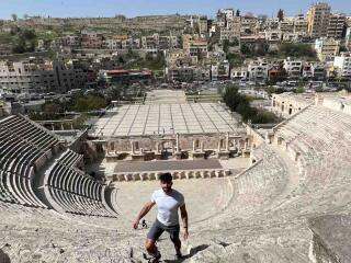 Stefan of Nomadic Boys standing on the steps of an amphitheater with a city in the background.