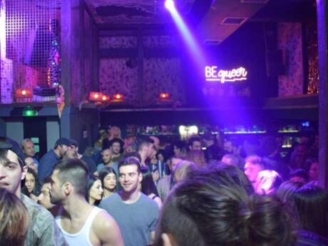 A packed dance floor lit up with purple lights at BEqueer gay club in Athens.