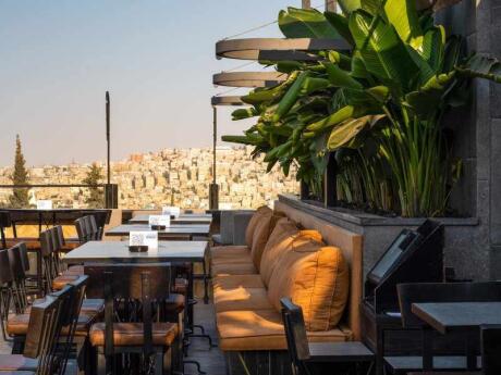 Sunny rooftop bar District with palm trees overlooking Amman.