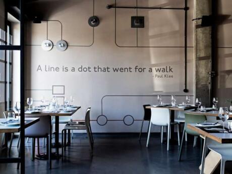 The chic interior of Prosopa Restaurant in Athens, with a quote on the wall saying "A line is a dot that went for a walk."