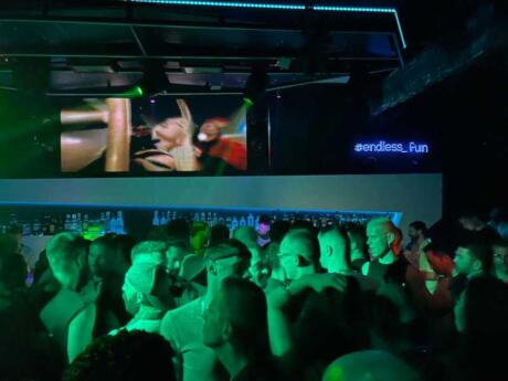 Lots of men lit up in green on the dark dance floor at Sodade2 gay club in Athens.