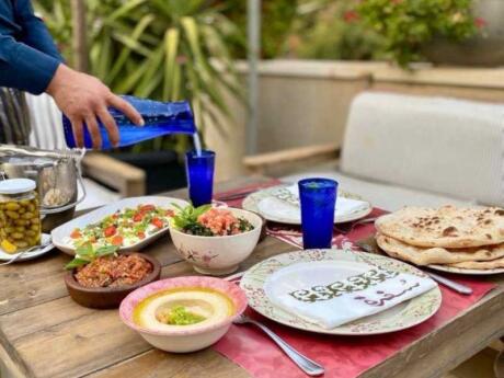 A garden table laid with plates of food and water at Sufra Restaurant in Amman.