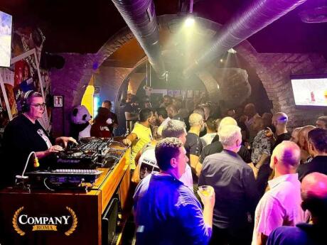 A packed dancefloor lit up in purple at Company Roma gay bar in Rome.