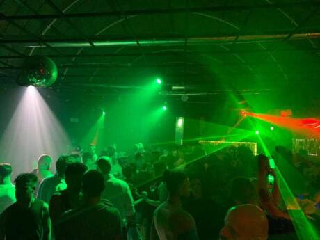 A packed dance floor lit up with green strobe lighting at Frutta e Verdura gay club in Rome.