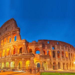 The Colosseum in Rome lit up at night with a golden glow.