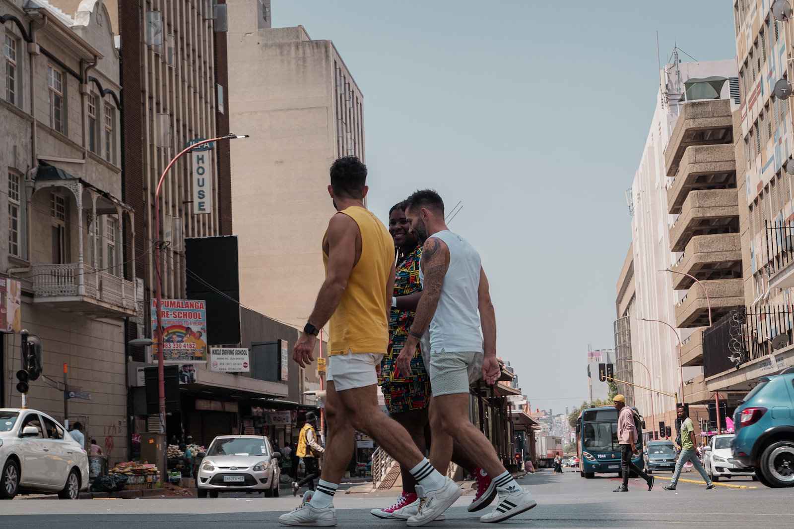 Gay couple Seby, Stefan and their local guide walking across a street in Johannesburg.
