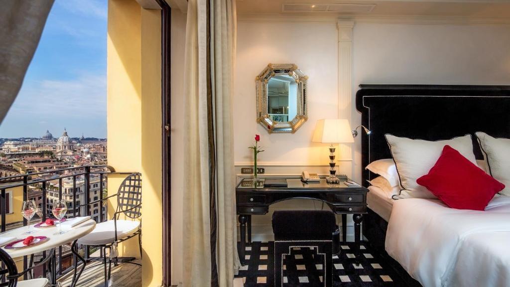 An elegant bedroom at Hassler Hotel in Rome with a private balcony overlooking the city on a sunny day.