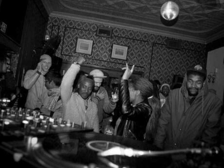 A black and white photo of locals dancing in front of a vinyl record deck at Kitcheners in Johannesburg.