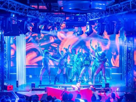 A group of performers on stage lit up with blues and purples at the Muccassina gay club in Rome.