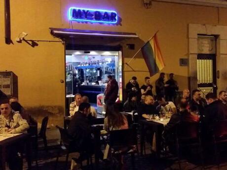 Lots of people sitting outside My Bar gay bar in Rome at night.