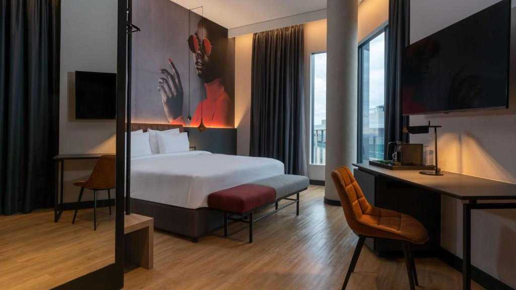 A stylish bedroom at the Radisson RED Hotel in Johannesburg with a mural of an African woman in shades of red above the bed.
