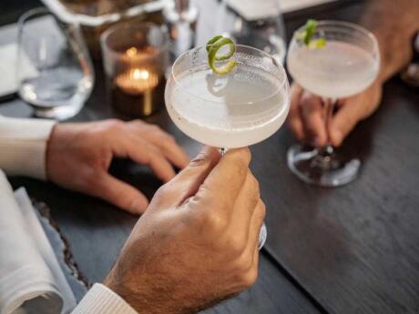 A close up of two sets of hands holding two cocktails on a table at the third place in Newtown, Johannesburg.