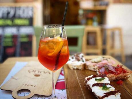 An antipasto platter with a cocktail on a table in front of Vulio Restaurant in Rome.