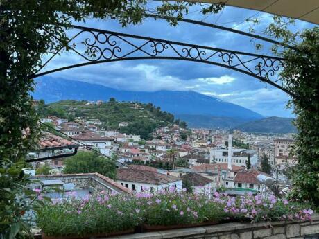 The pretty town Berat seen from on top of a hill underneath a trellis in Albania.