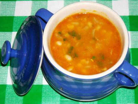 A white and blue dish with the lid off showing a tomato based soup.