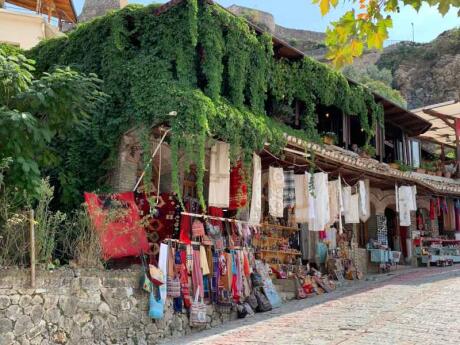 A cute local stall selling clothing outside an old building covered in vines in Kruje, Albania.