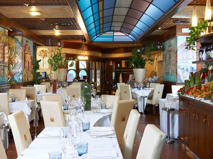 The elegant interior of Osteria Mamma Rosa in Milan with a blue glass ceiling and beautiful murals on the walls.