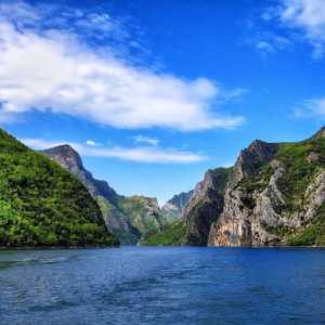 A rocky mountainous landscape as seen from the water on a beautiful sunny day with blue skies.