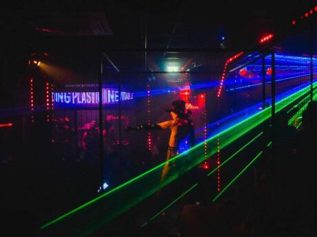 A performer in a cage at Club Plastic in Milan with rainbow strobe lights.