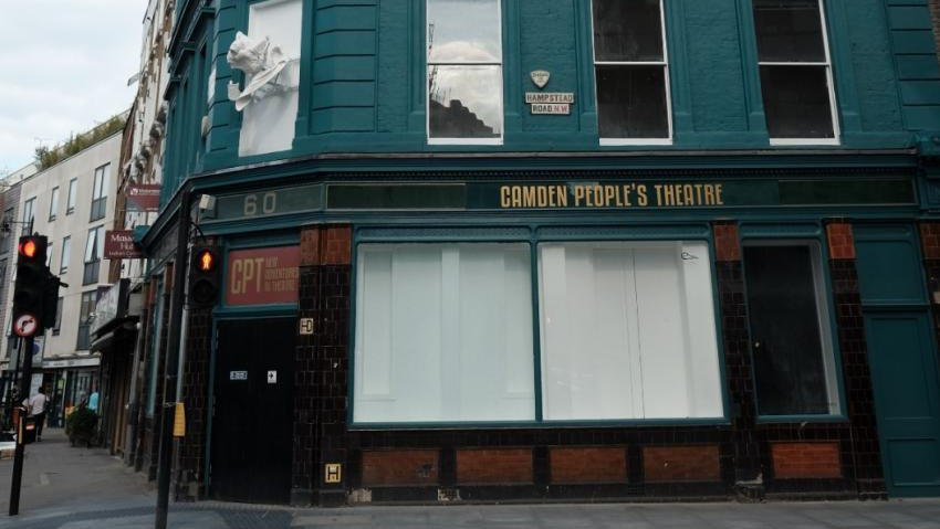 The exterior of the Camden People's Theatre in London, a dark green/blue building with a white sculpture hanging off one of the second-floor windows.