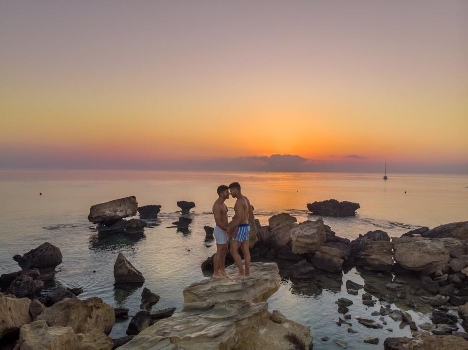 Stef and Seby, gay couple embracing at Kapparis beach in Cyprus at sunrise.